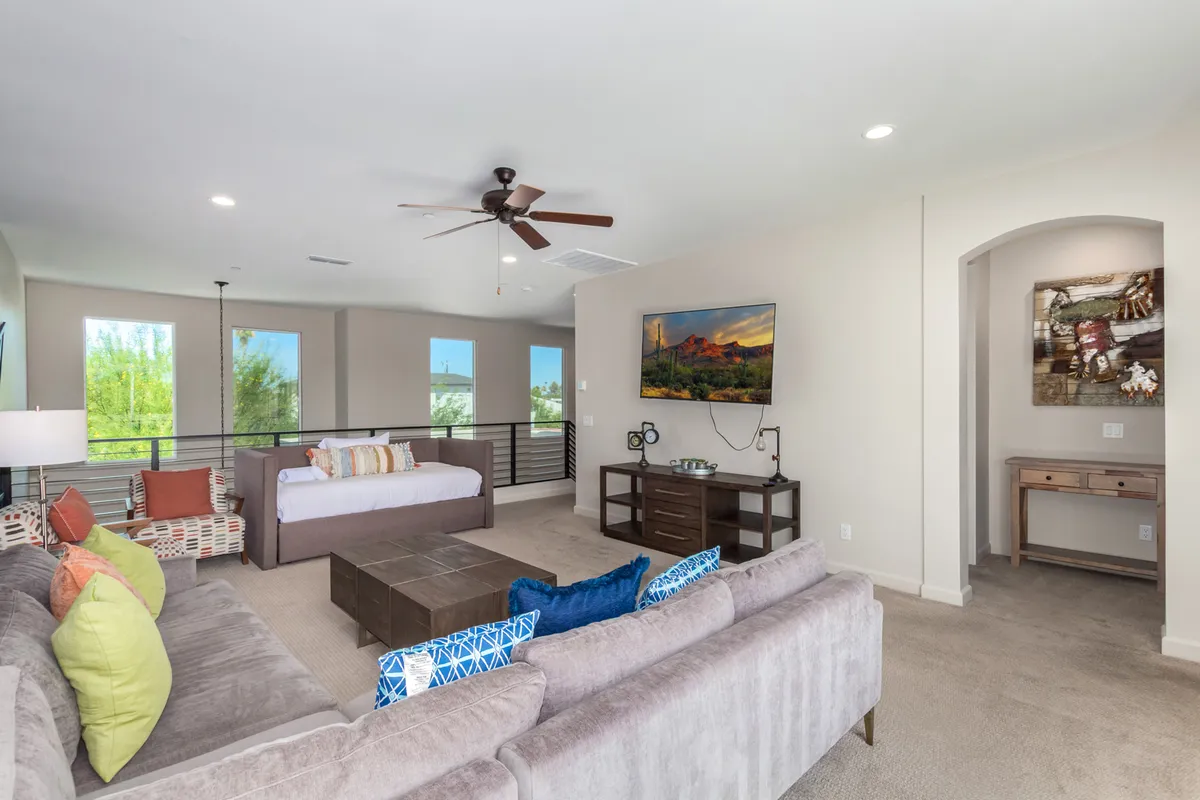 This image displays a spacious main living room with a large sectional sofa, a central coffee table, a TV, and decorative art pieces adorning the walls. The lounge area is designed for both relaxation and group gatherings, with ample seating and a warm, casual ambiance.