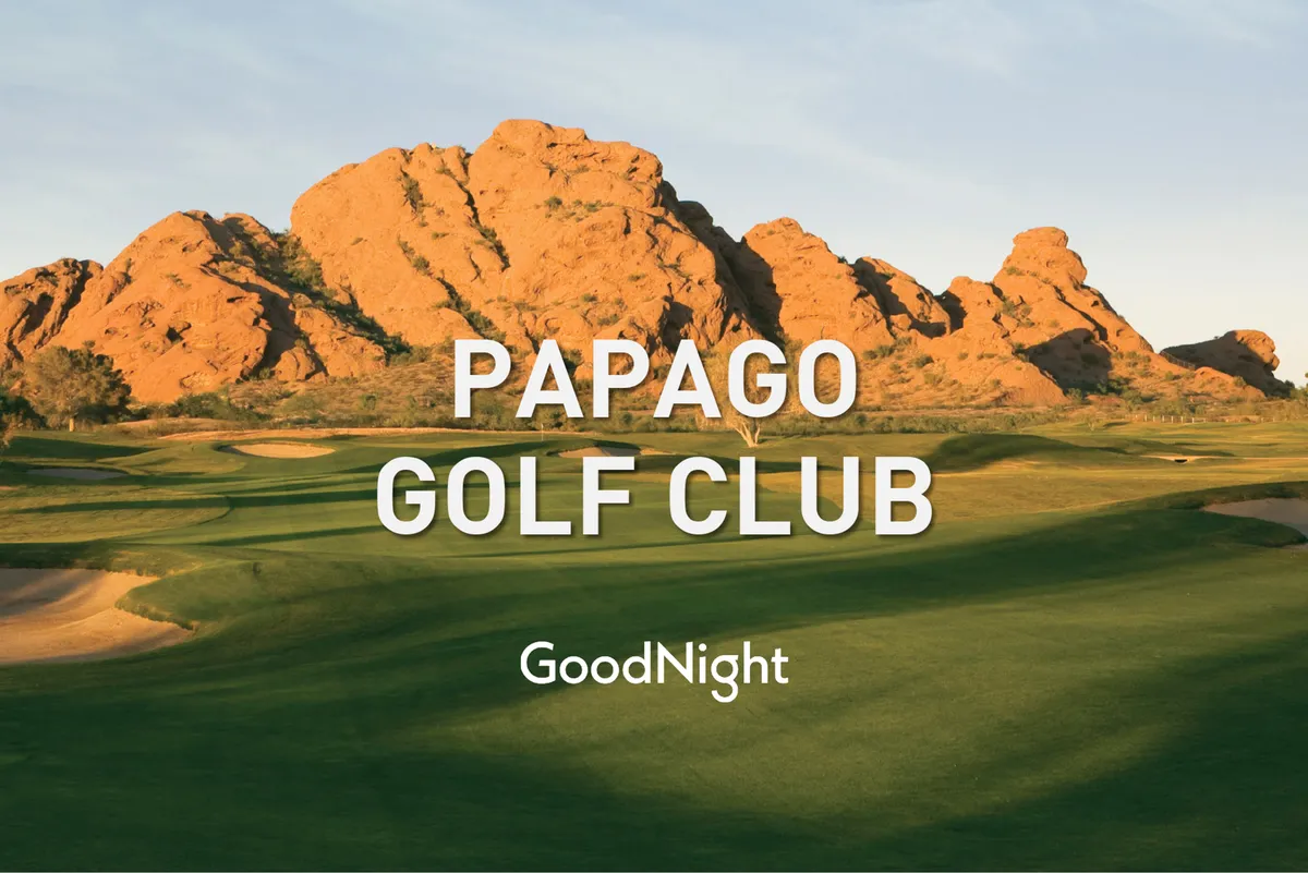 A scenic view of a well-manicured golf course with lush green fairways set against a dramatic mountain backdrop. The sun is low on the horizon, suggesting either sunrise or sunset, and the vastness of the course invites active team-building or relaxed networking events.