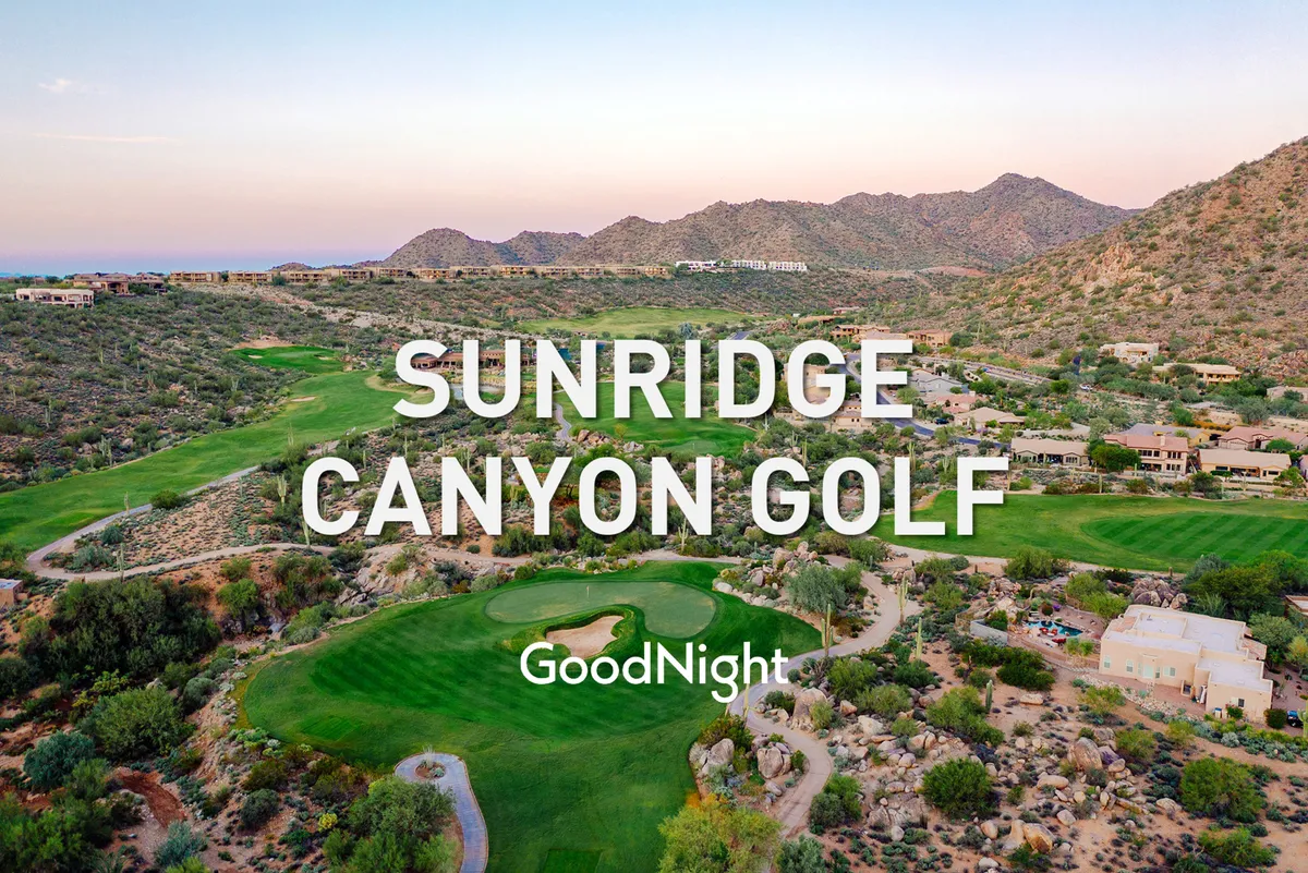 This image captures a panoramic view of a lush golf course nestled among luxury homes and picturesque mountains. The setting sun bathes the scene in a golden light, highlighting the manicured greens and peaceful ambiance—ideal for both golfing and post-round relaxation.