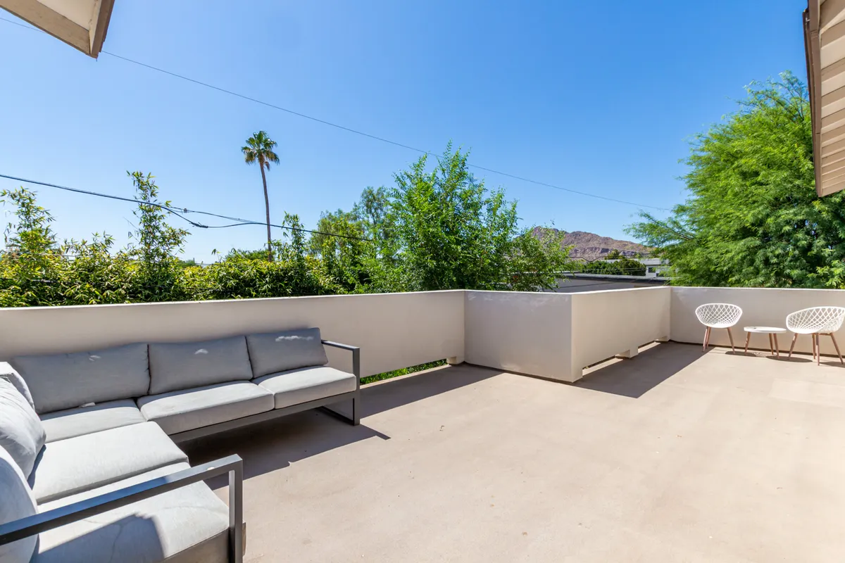 A tranquil outdoor seating area surrounded by lush greenery with a breathtaking view of nearby mountains. The comfortable lounge furniture invites relaxation, whether for intimate conversations or casual meetings.