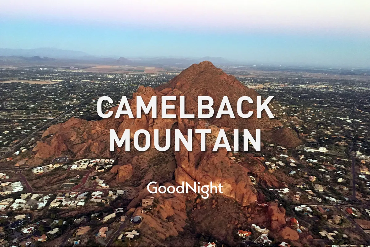 A breathtaking view of Camelback Mountain looms over the surrounding residential area, with expansive blue skies and inviting sunset hues. The image conveys the allure of local hiking trails and outdoor adventures only moments away from the home.